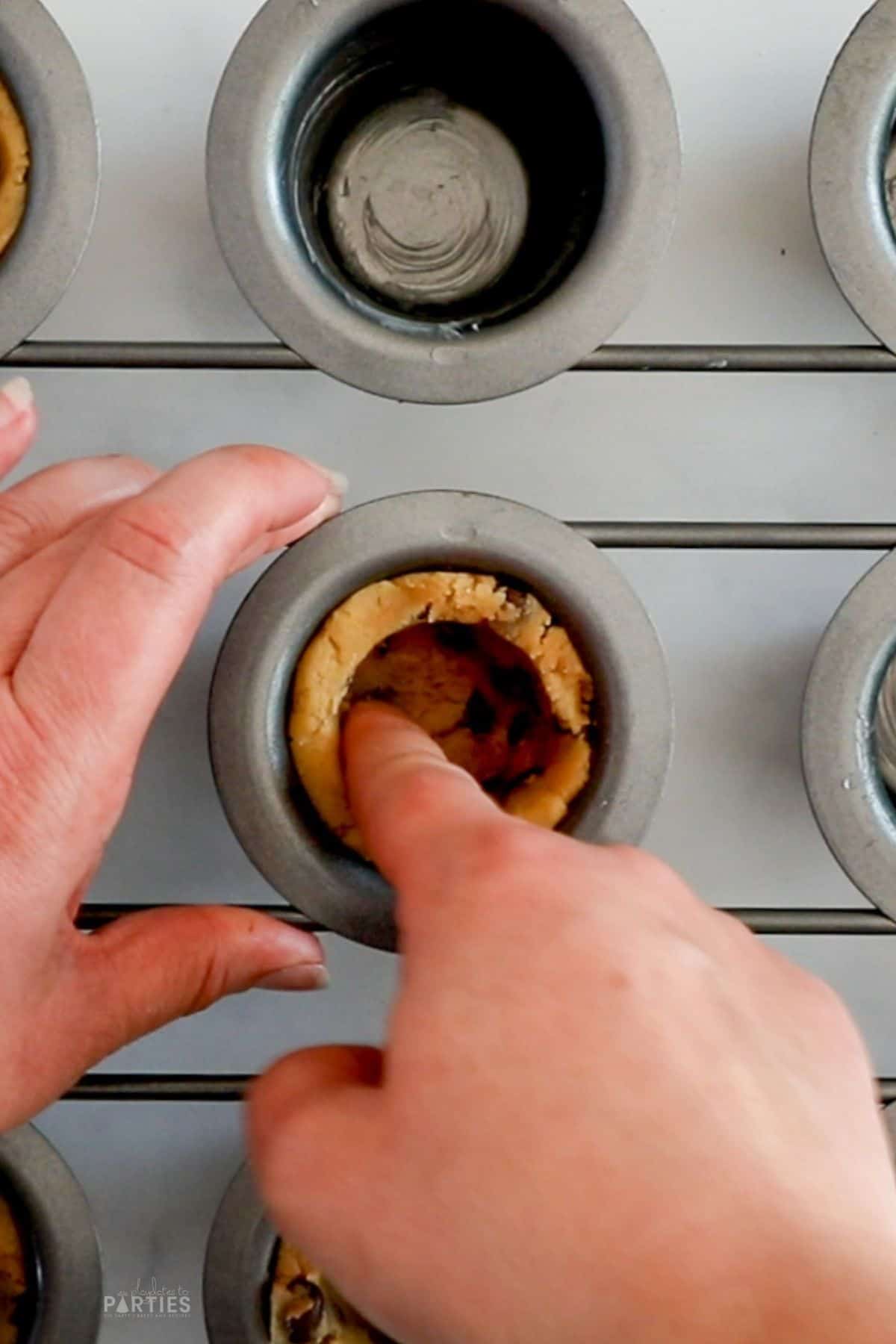 Forming chocolate chip cookie cups in a popover pan.