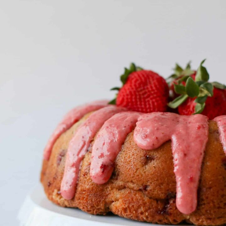 A bundt cake with thick strawberry glaze and fresh strawberries in the middle.