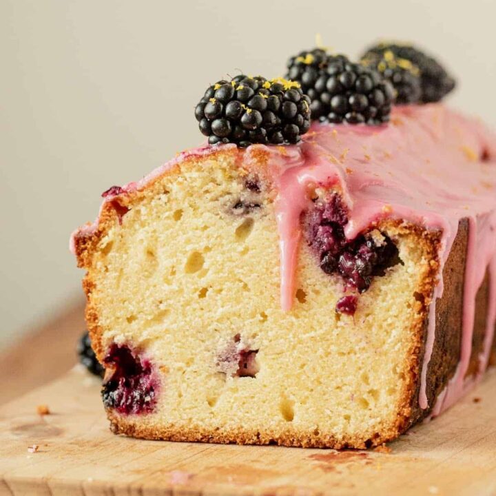 Lemon blackberry bread with pink blackberry glaze and fresh blackberries on top.