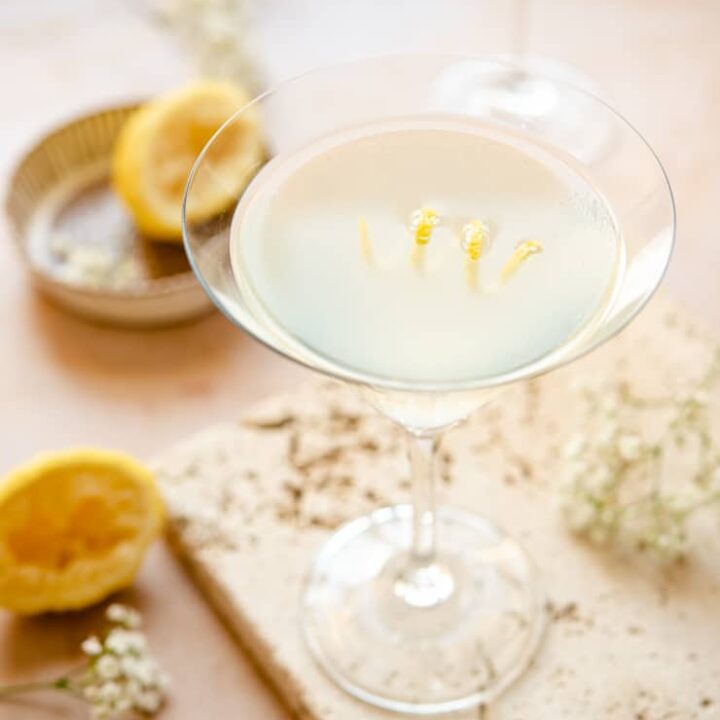 A white limoncello cocktail in a martini glass with a lemon peel curl.