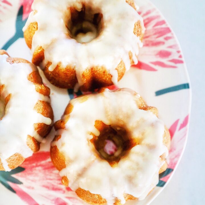 Mini citrus bundt cakes on a colorful plate with white glaze.