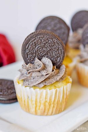 An Oreo cupcake with Oreo frosting on a white plate.