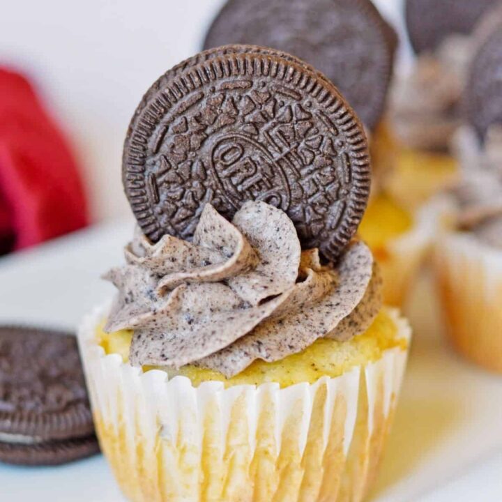 An Oreo cupcake with Oreo frosting on a white plate.