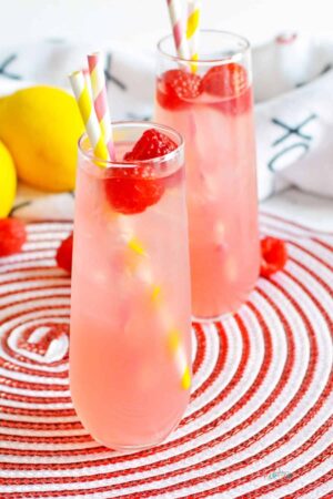 Two raspberry vodka lemonade cocktails on a red and white trivet.