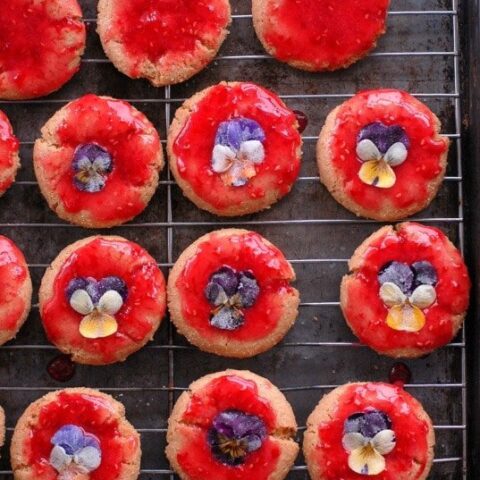 Sugar cookies with raspberry glaze garnished with sugared fresh pansies.