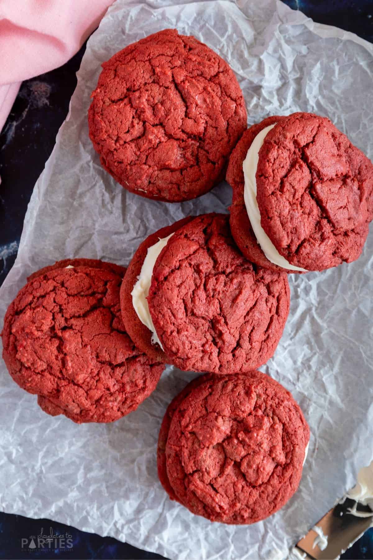 Red velvet sandwich cookies on a piece of parchment paper.