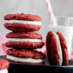 3 red velvet cookie sandwiches stacked on a small black plate.