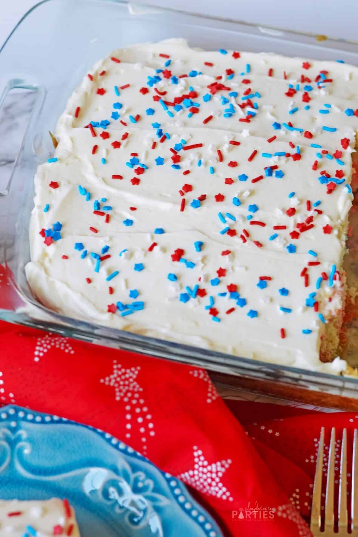 A sheet cake in a glass pan with red, white, and blue sprinkles.