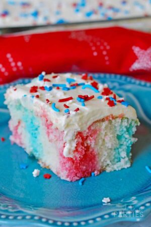 A slice of 4th of July poke cake on a blue plate.