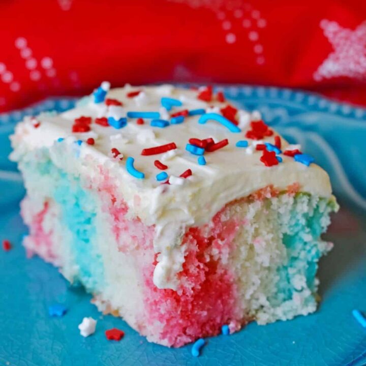 A slice of 4th of July poke cake on a blue plate.