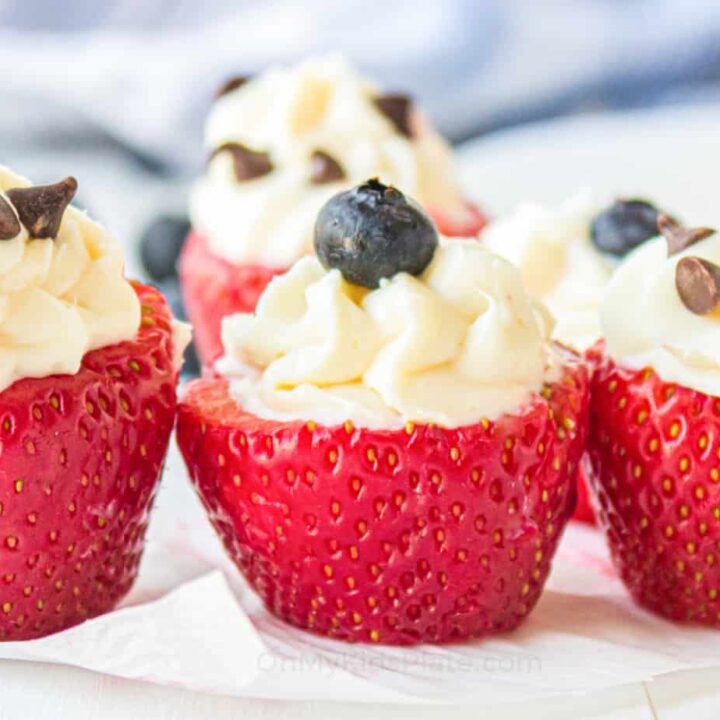Fresh strawberries stuffed with cream cheese, garnished with chocolate chips and blueberries.