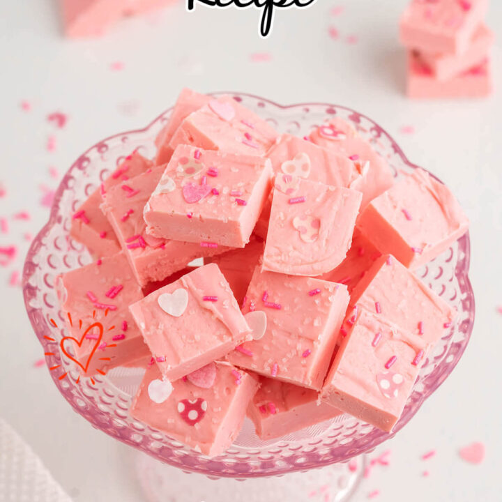 Squares of pink fudge in a footed glass bowl.