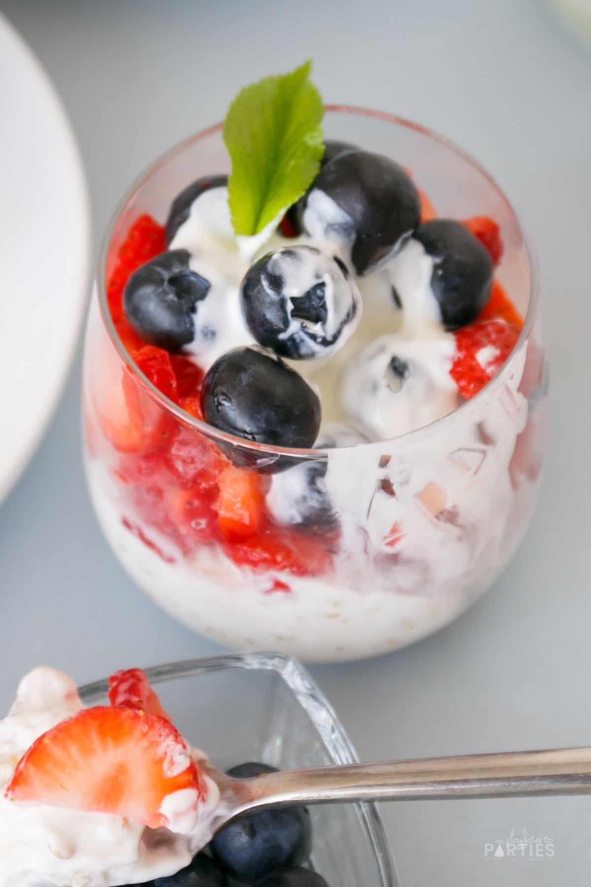 A cup with yogurt and berries with a bite taken out.