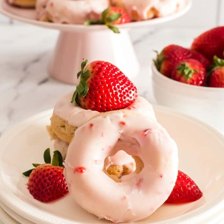 Donuts covered with light pink strawberry glaze and fresh strawberries.