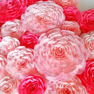A wall covered with paper flowers in different shades of pink.