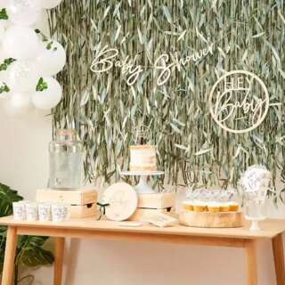 Green, gold, and white baby shower decorations in front of a dessert buffet.