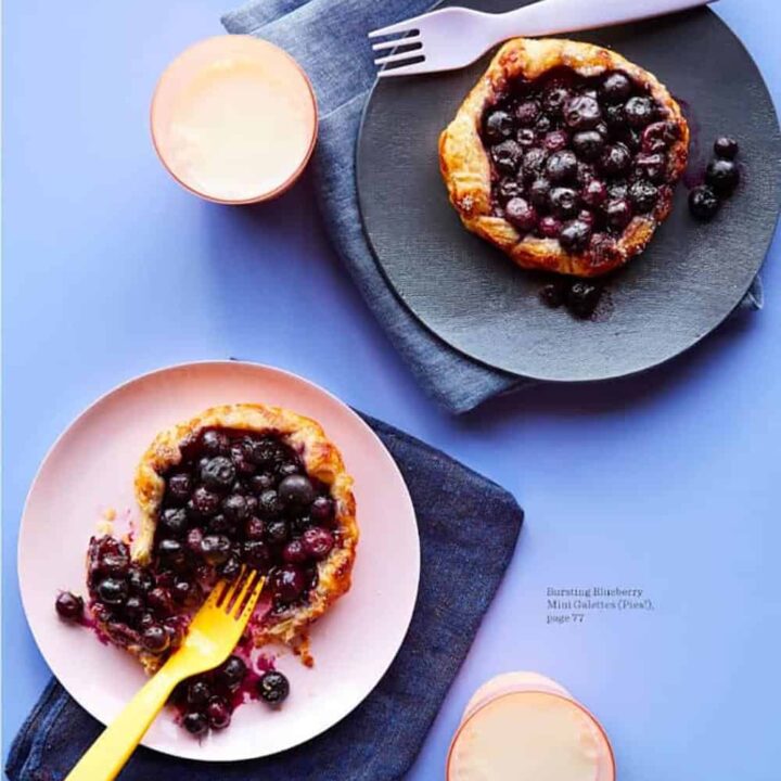 Mini blueberry galettes on pink and blue plates.