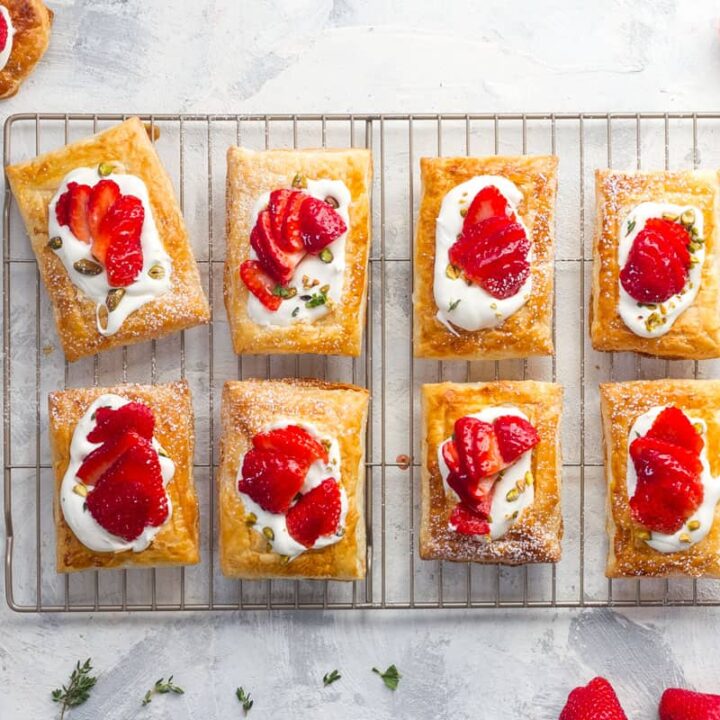 Strawberry tarts on a cooling rack with fresh strawberries.