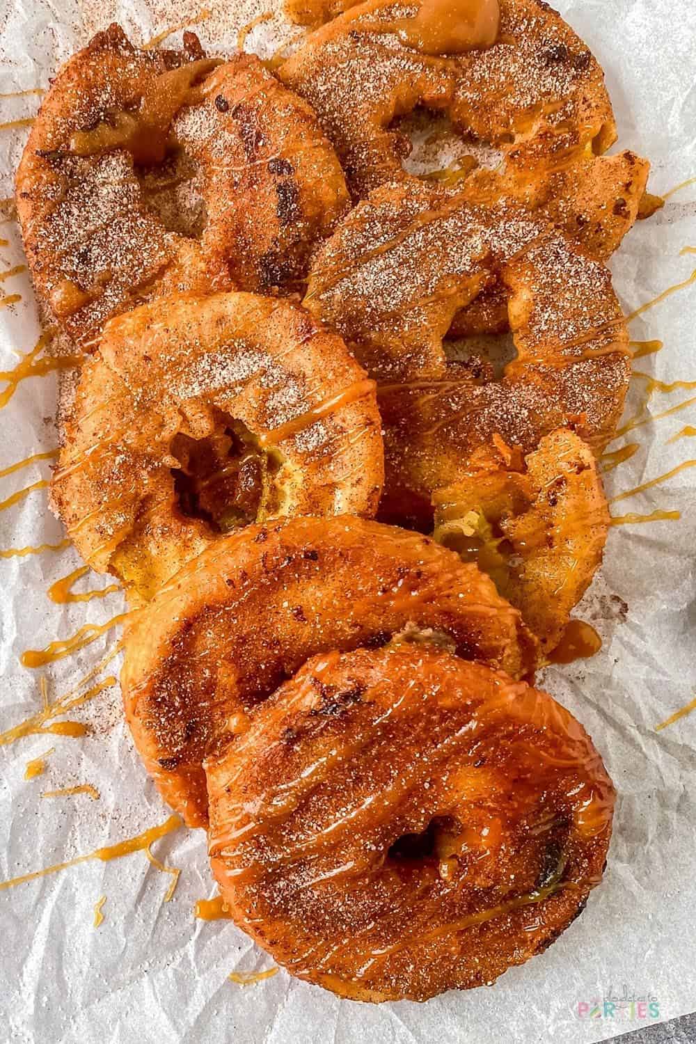 Overhead view of a pile of fried apple rings drizzled with caramel.
