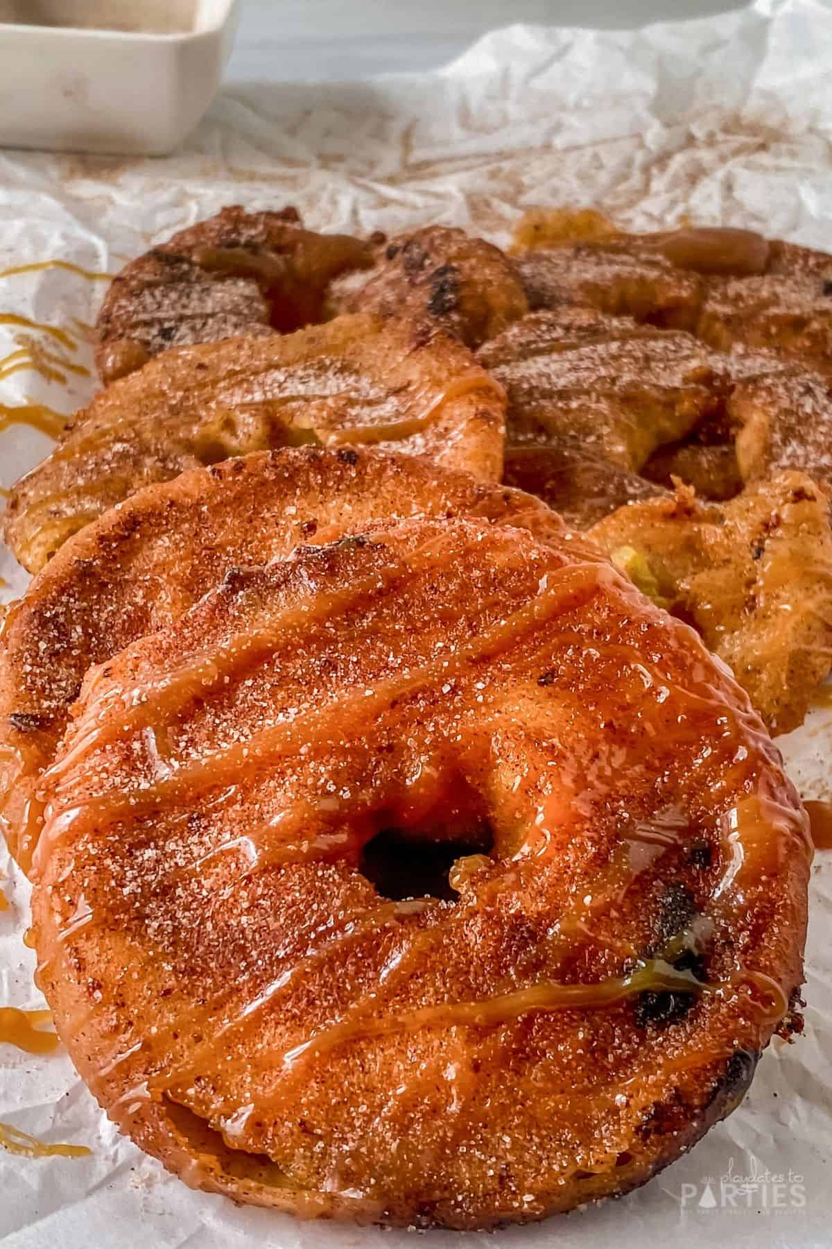 Close up of a fried apple ring with cinnamon sugar and caramel drizzle.