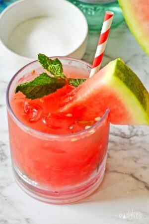 Overhead view of a lowball glass filled with watermelon mojitos and garnished with fresh mint and a watermelon wedge.