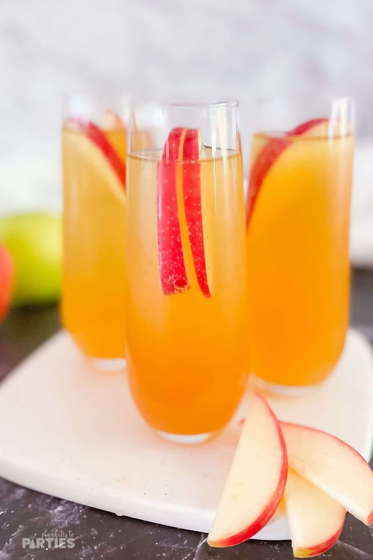 Three apple cider mimosa cocktails sitting on a white tray.