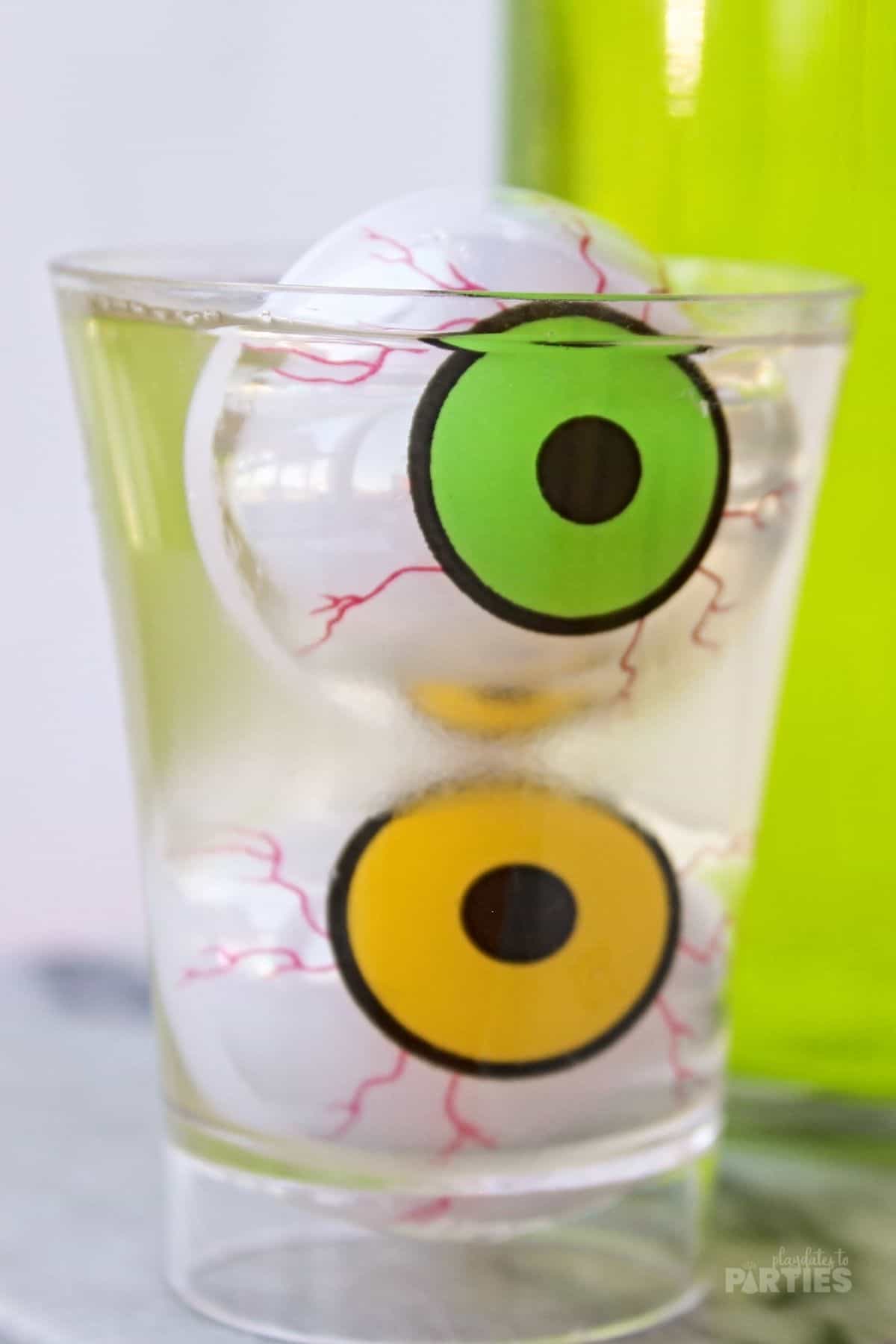 A clear jello shot with two gummy eyeballs floating inside.
