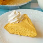 A slice of creamy pumpkin cheesecake on a white plate.