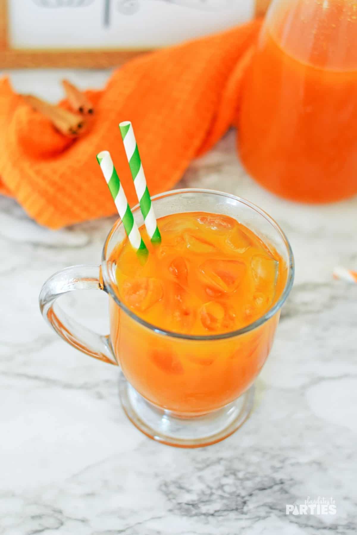 A mug filled with pumpkin juice with two green paper straws.