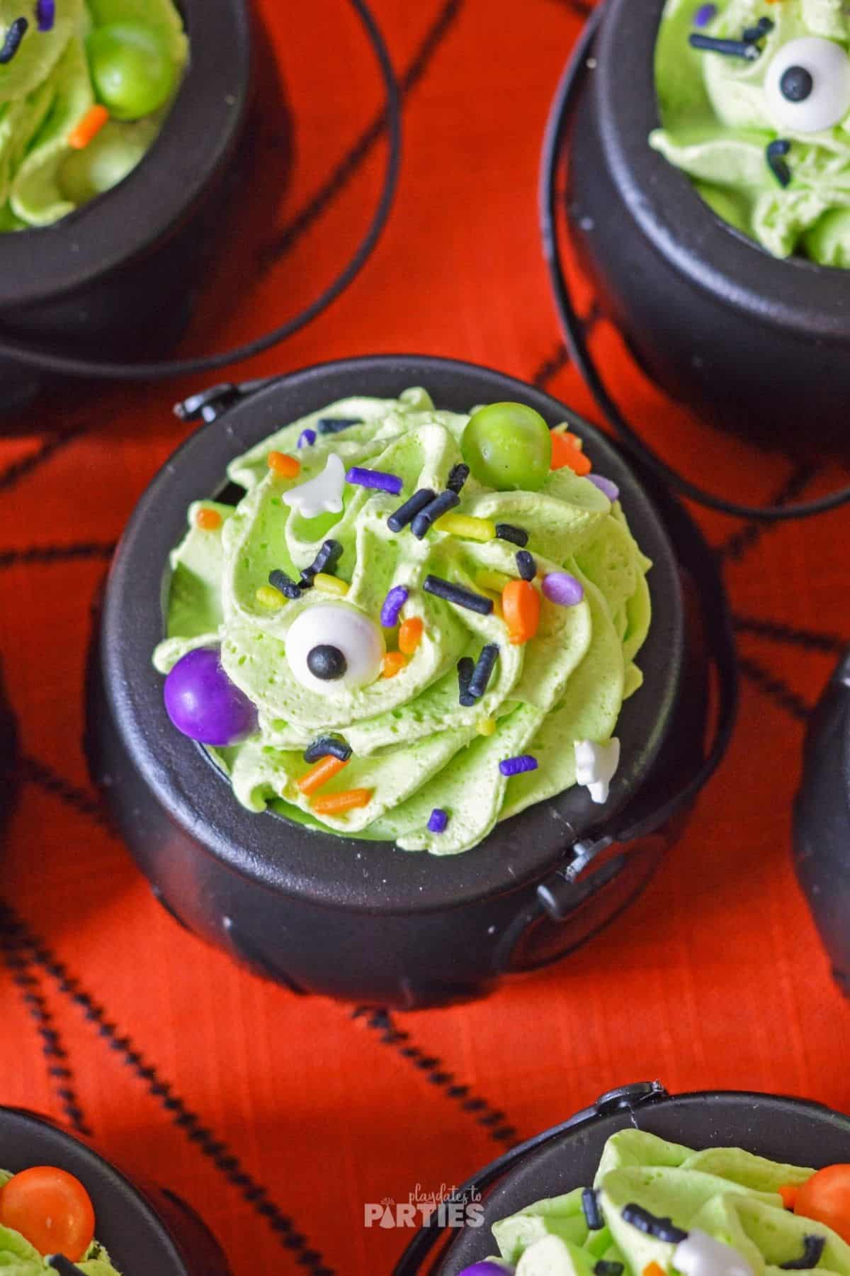 Top down view of a kids Halloween snack with green whipped cream and spooky Halloween sprinkles.