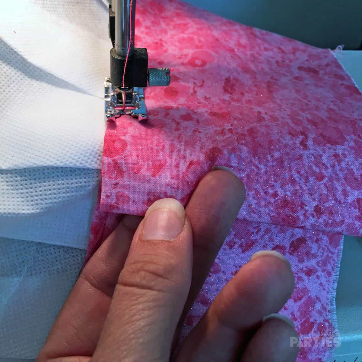 Fabric being sewn onto a chef hat while a woman's hand folds over the end of the strip.