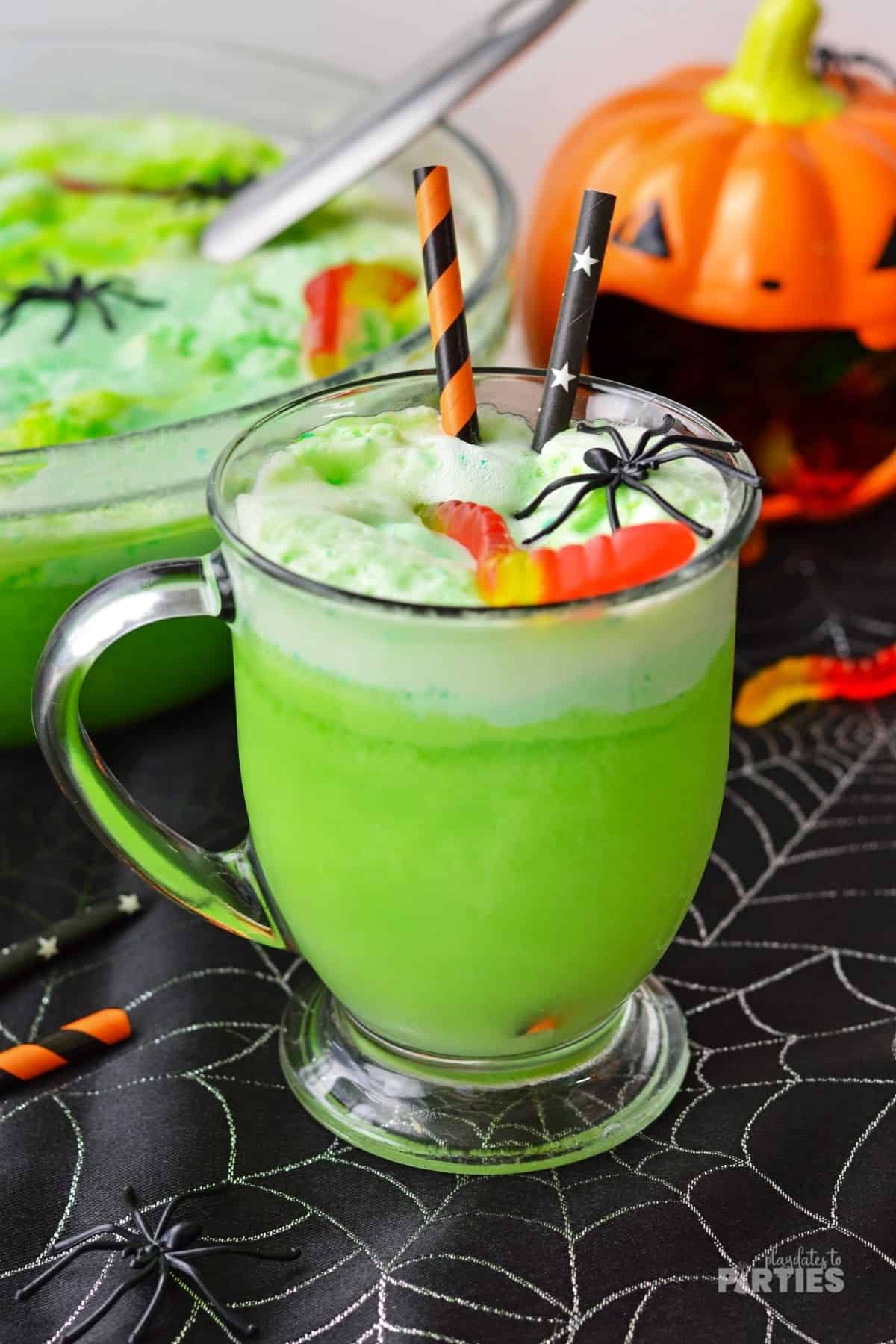 A glass mug filled with green witches brew Halloween party punch.