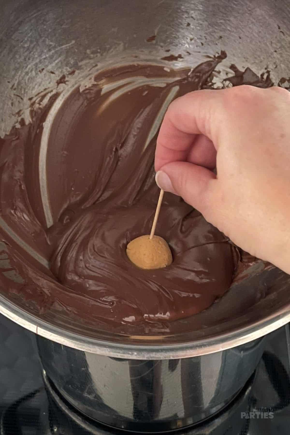 Dipping candy in melted chocolate to coat.