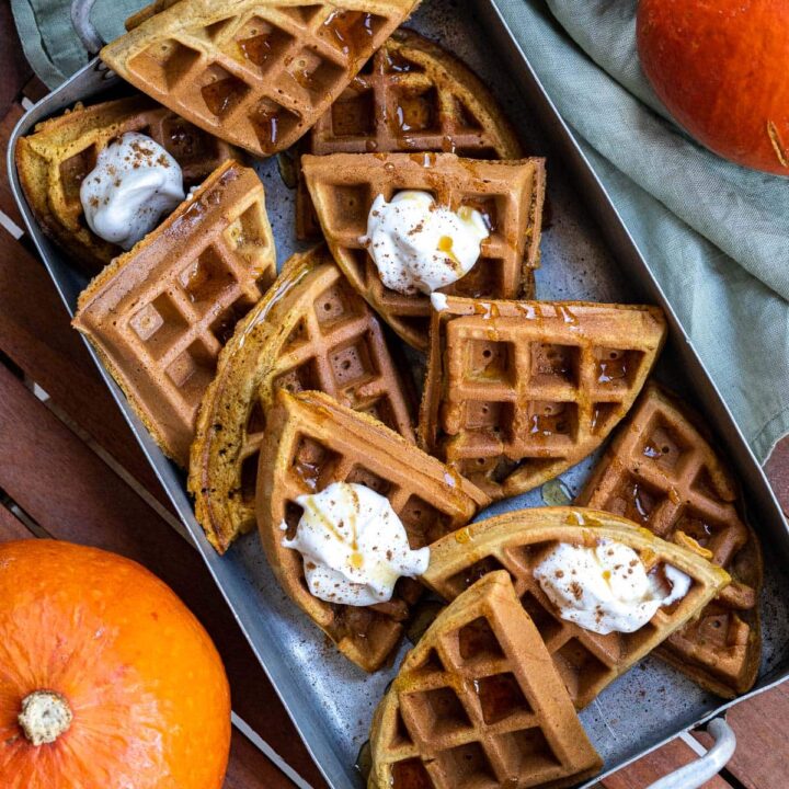 A baking tray holds sections of belgian style waffles with butter melting on top.
