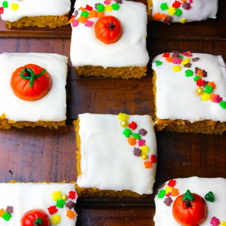 Squares of pumpkin bars are decorated with frosting and fall leaf sprinkles.