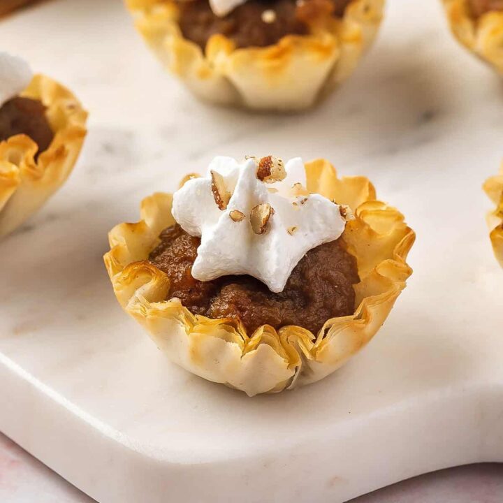 Mini strudel cups filled with pumpkin and pecans, and topped with whipped cream.