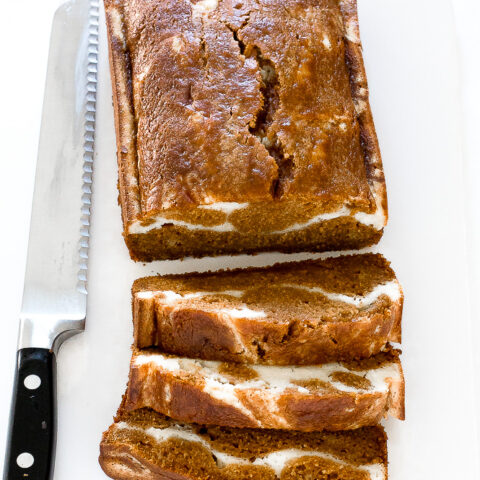 Cream cheese pumpkin bread on a white cutting board.