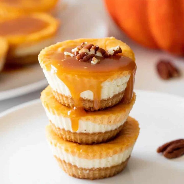 Mini keto pumpkin cheesecakes stacked and then topped with caramel.