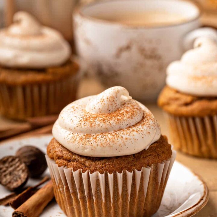 A pumpkin spice cupcake sits on a plate amidst a table set for afternoon tea.