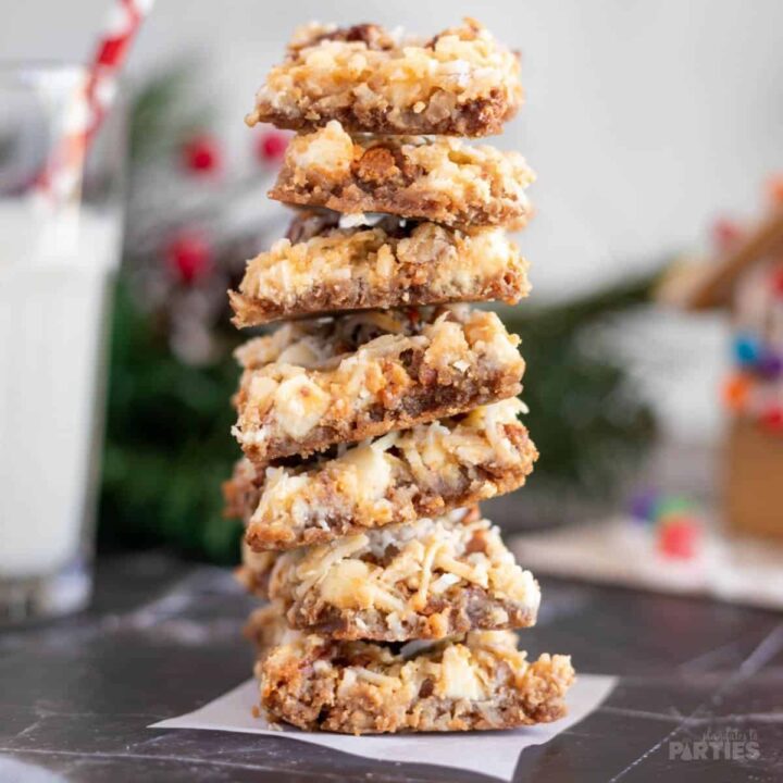 A stack of 7 dessert bars with white chocolate chips, coconut, and a gingersnap crust.