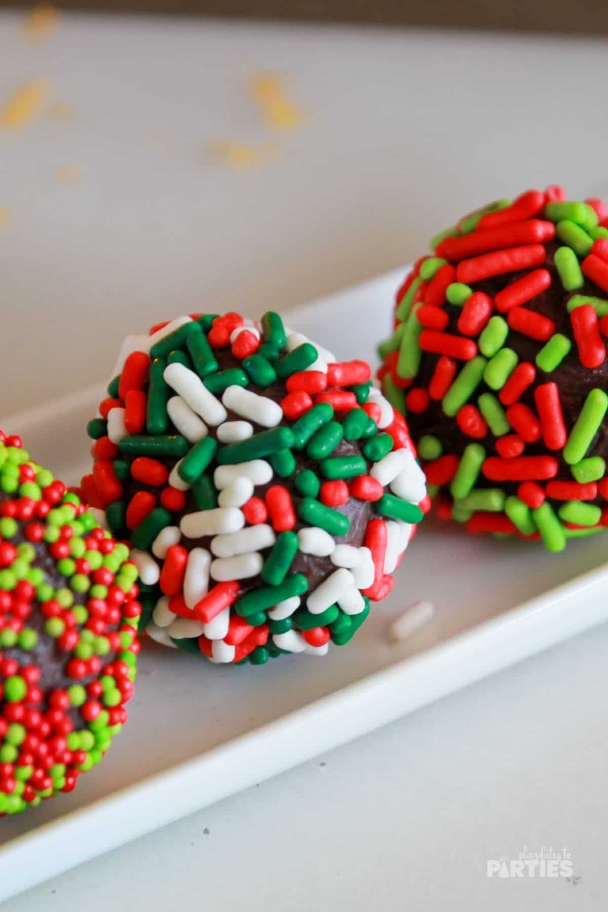 Sprinkles covered holiday truffles with orange zest nearby.