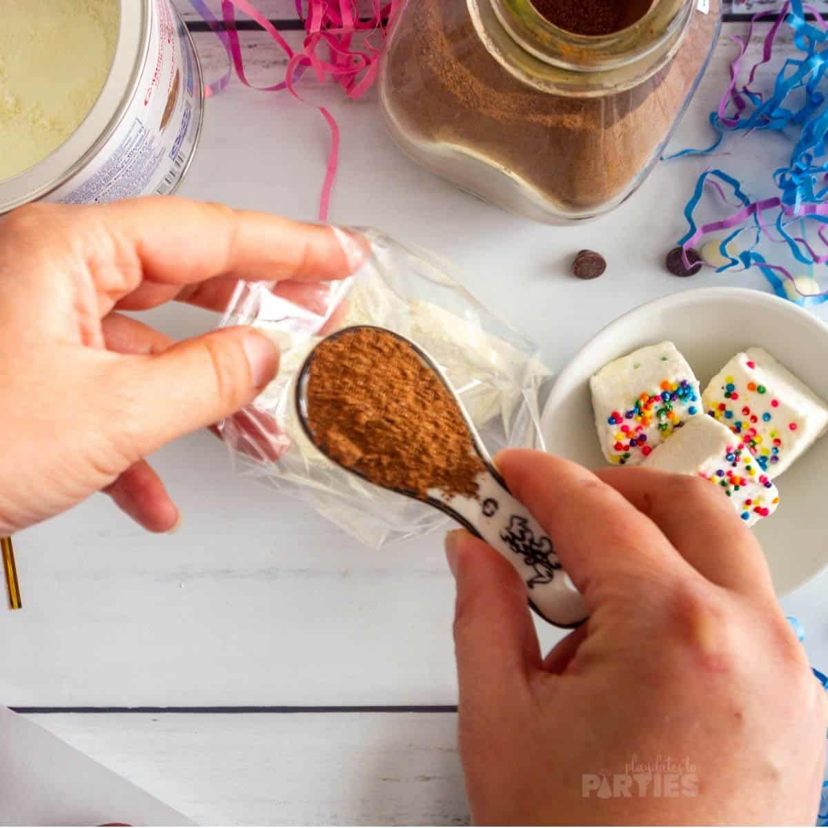 A woman's hand pouring hot cocoa mix into a favor bag.