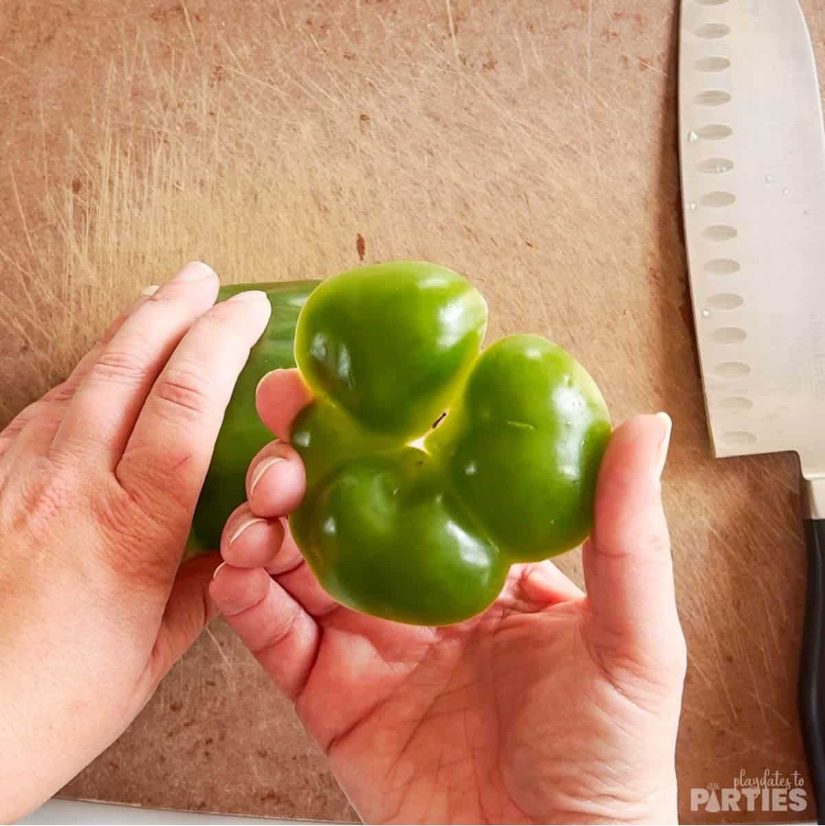 Cutting off the bottom of a bell pepper.
