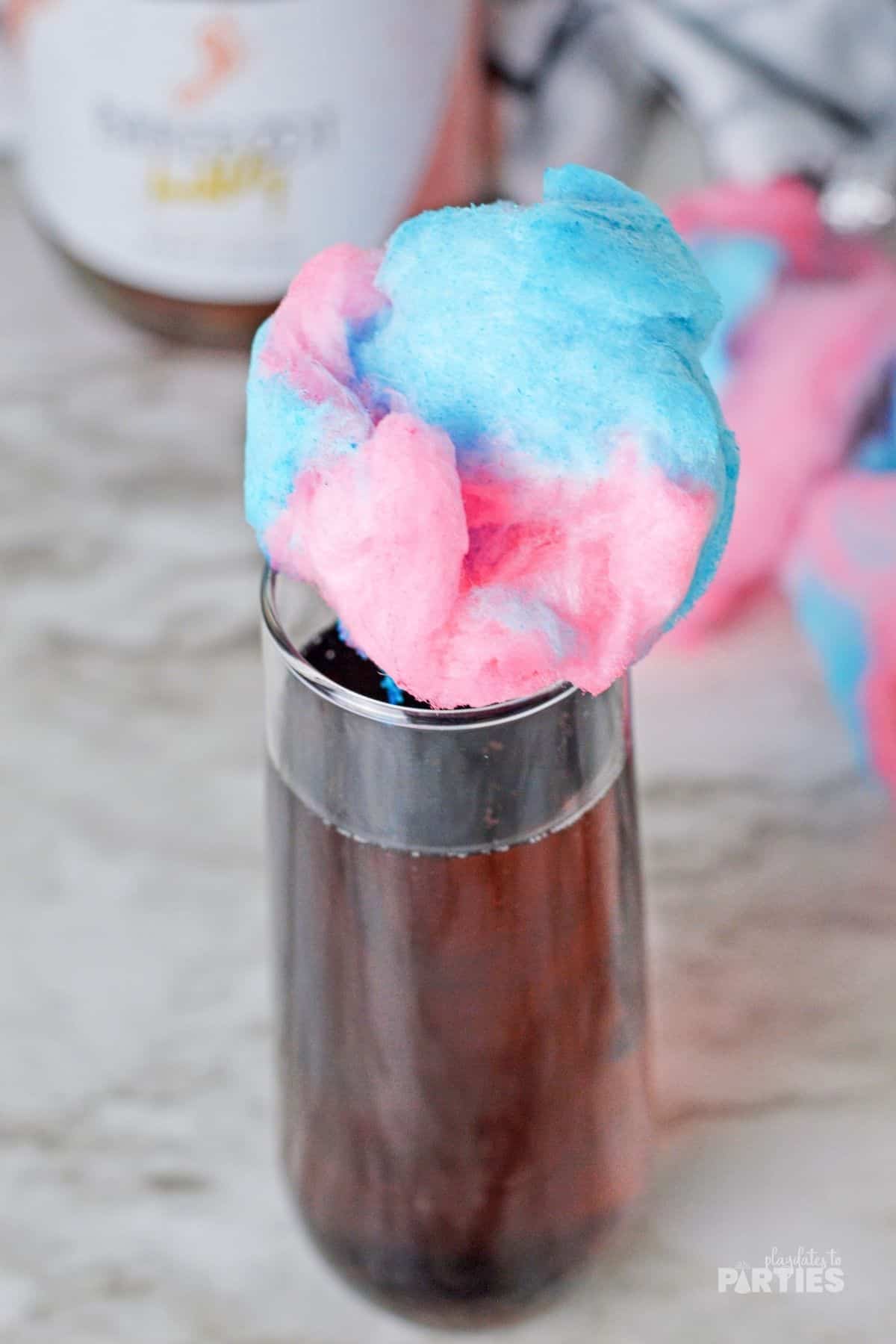 A champagne flute with blue and pink cotton candy on top.