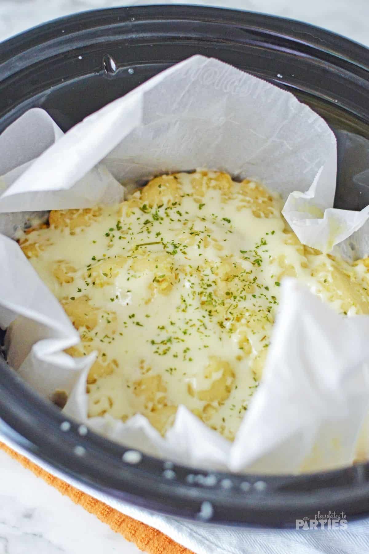 A slow cooker with cheesy bread as an appetizer.