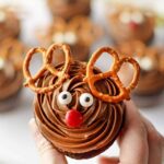 A woman's hand holding a chocolate cupcake for Christmas.