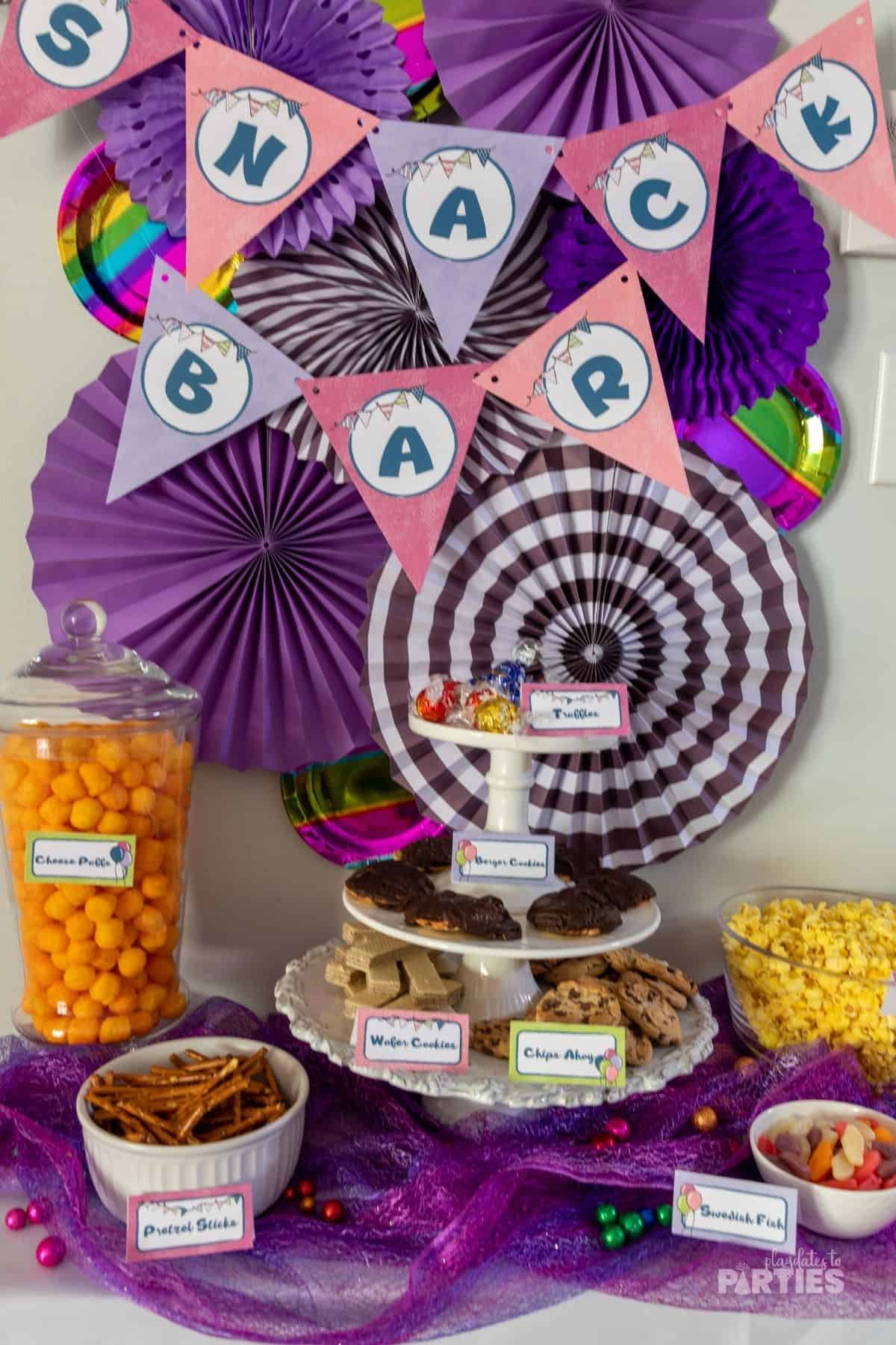 A snack bar with purple and white paper fans, and a pink and purple banner.