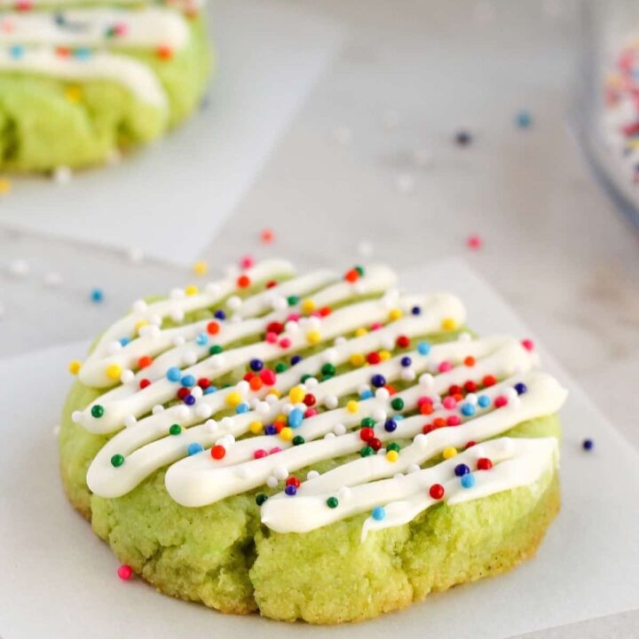 A lime cookie decorated with white chocolate and sprinkles.