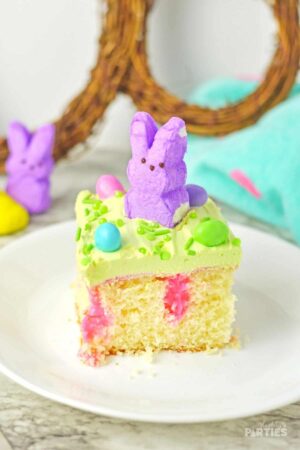 A slice of Easter poke cake with peeps and M&Ms.