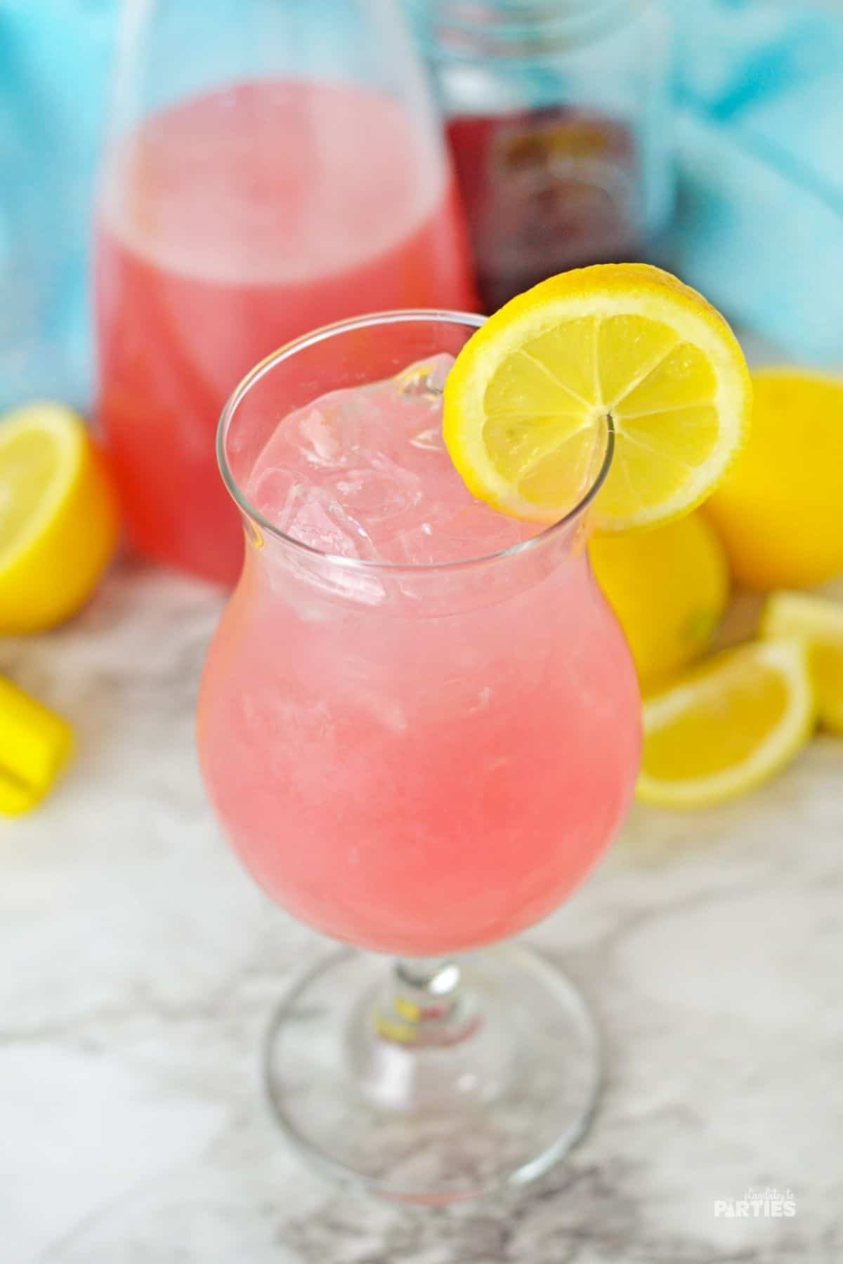 A hurricane glass filled with pink lemonade.